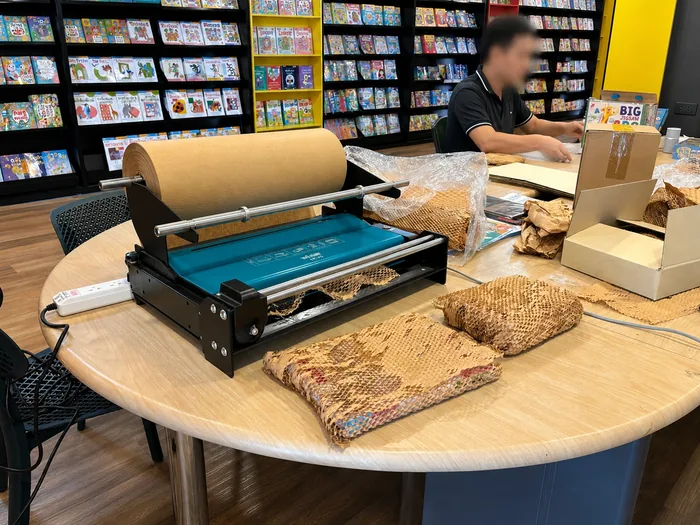 ร้านหนังสือใช้เครื่องขึ้นรูปกระดาษรังผึ้ง ห่อหนังสือก่อนลงกล่องบนโต๊ะแพ็คหน้าร้าน